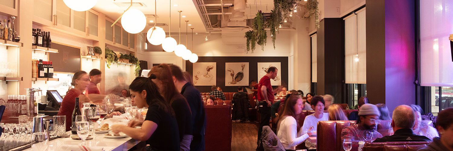 1500x500-interiorService-barAndDining Gussie's busy restaurant in the evening with a view of a dining room and bar