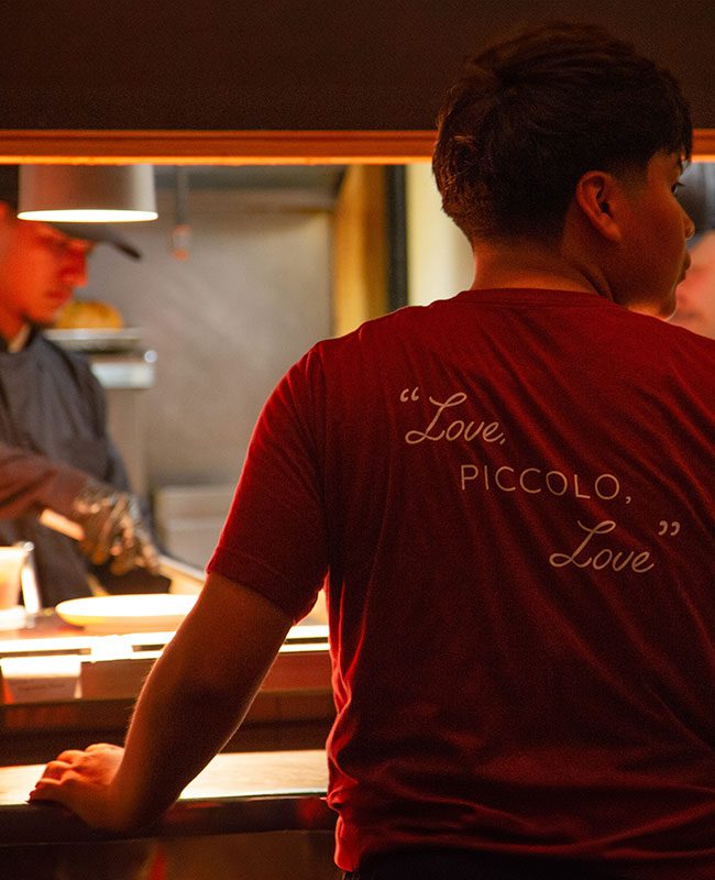 Back of staff's shirt that reads, "Love, Piccolo, Love."