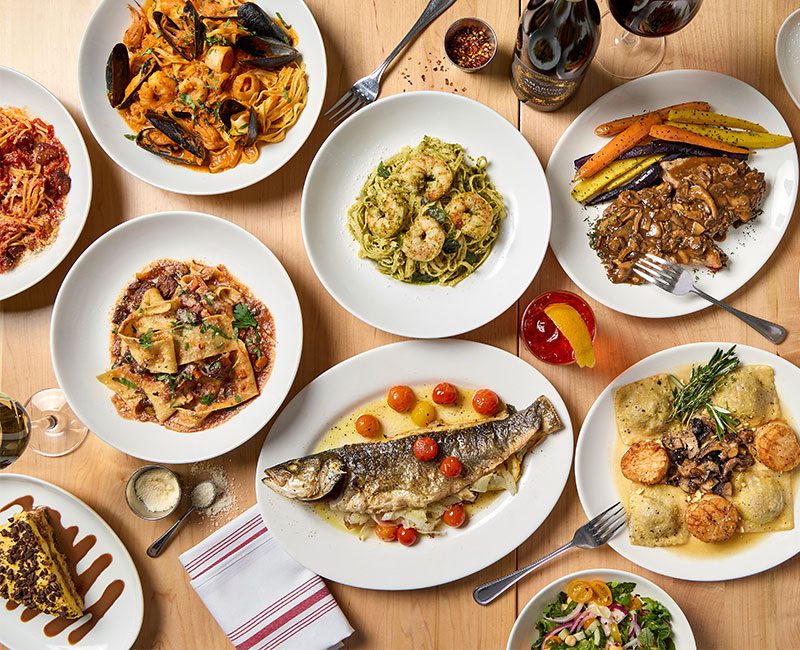 Overhead table shot of multiple Gussie's menu dishes, including many pastas