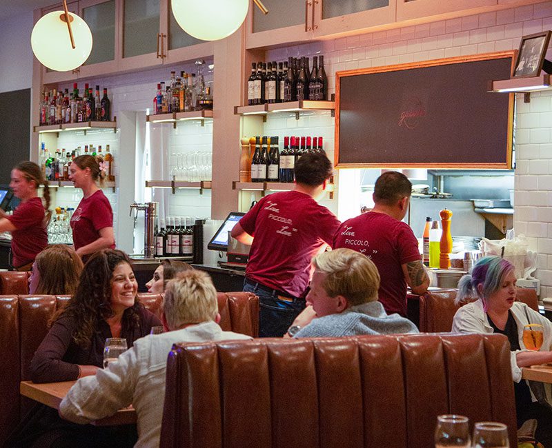 Picture of patrons dining in a booth, smiling and talking